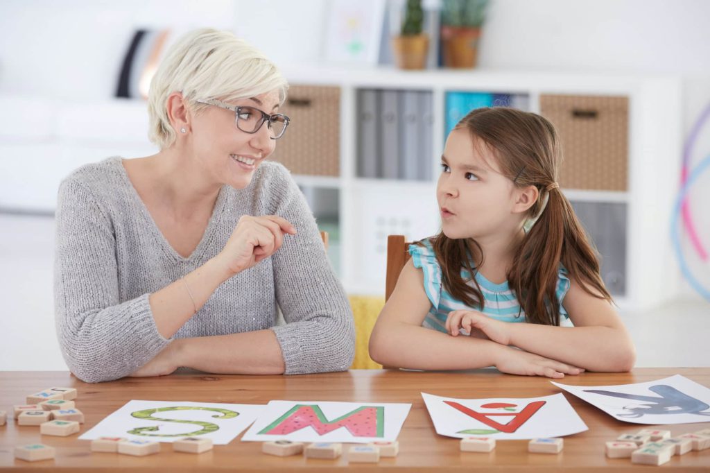 Child studying alphabet with teacher