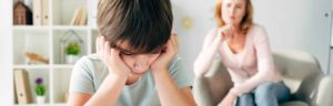 panoramic shot of sad kid with dyslexia and child psychologist on background